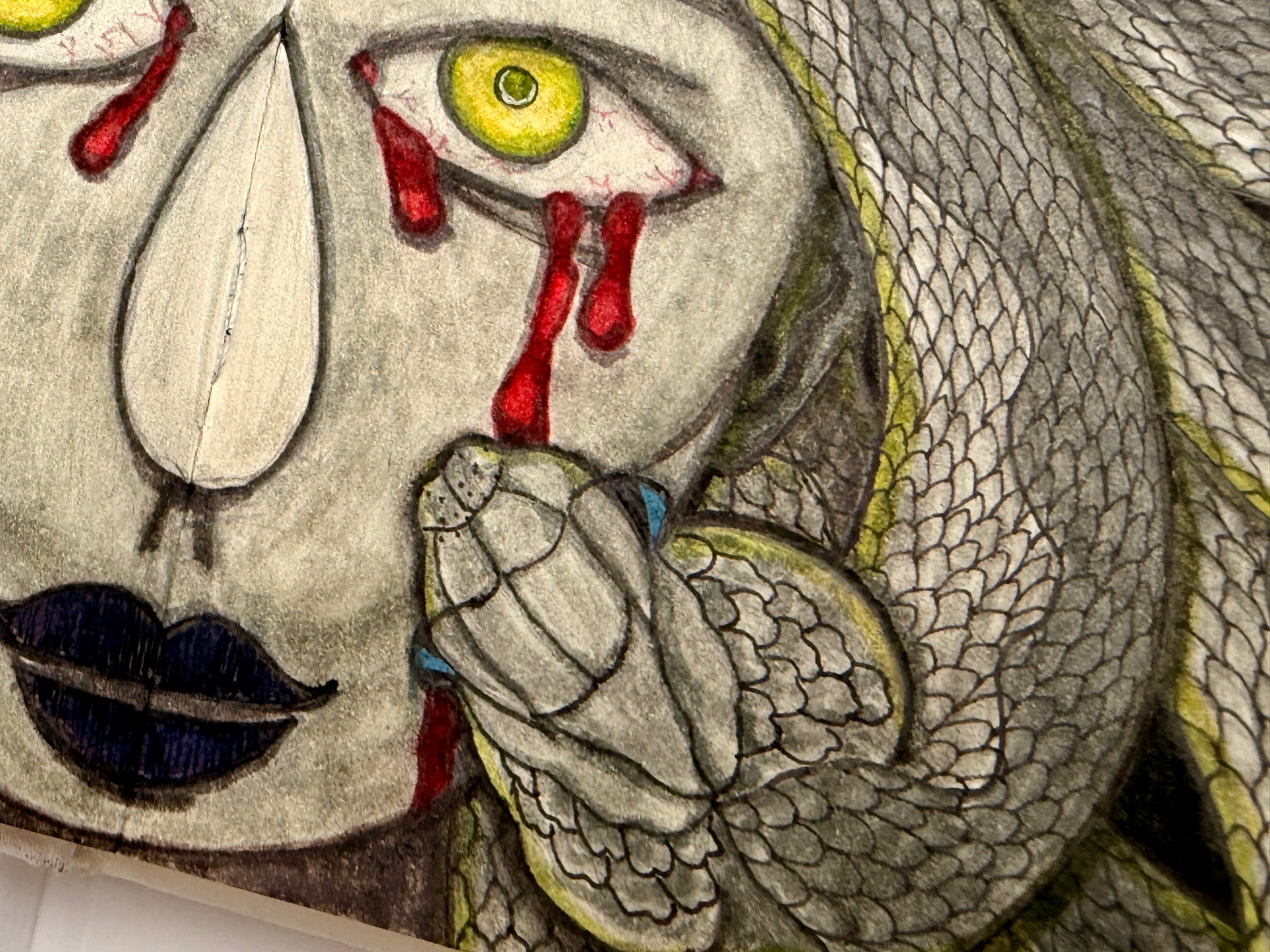 A close view of one side of the face, angled so the grain of the paper catches the light. A single yellow slit-pupil eye weeps thick red tears above a dark navy lip, beside a scaled hand and the banded coils of a snake edged in yellow.